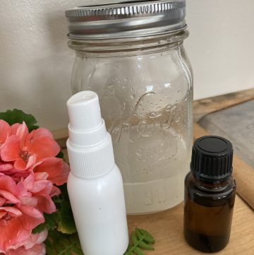 homemade bug and tick spray in a mason and jar and a spray bottle with an essential oil bottle beside them