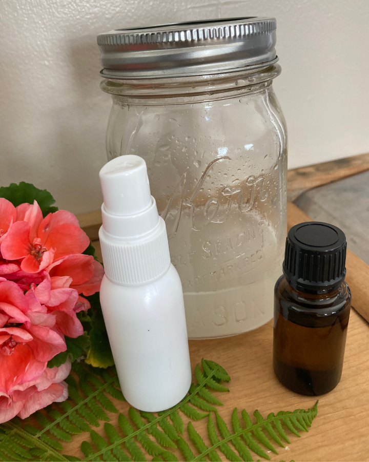 bug repellant in a mason jar and spray bottle with an essential oil bottle beside it