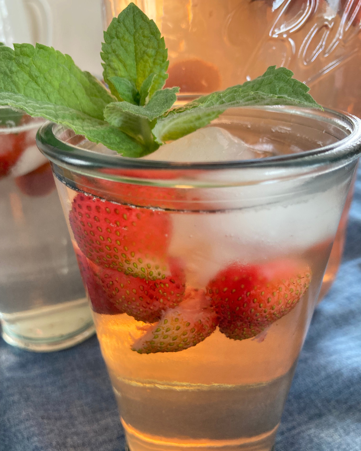 a glass with strawberry mint iced tea and strawberries