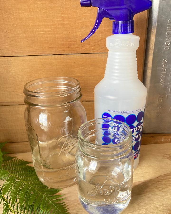 two mason jars beside a sprayer bottle of glass cleaner