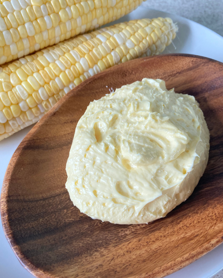 homemade butter on a plater beside some corn on the cob