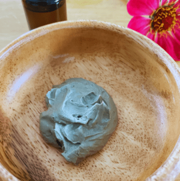 a bowl with bentonite clay mask beside essential oils