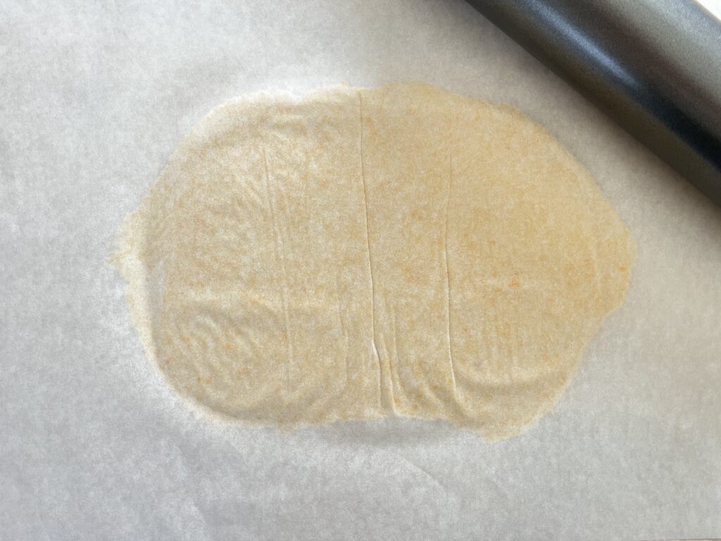 dough between two pieces of parchment paper
